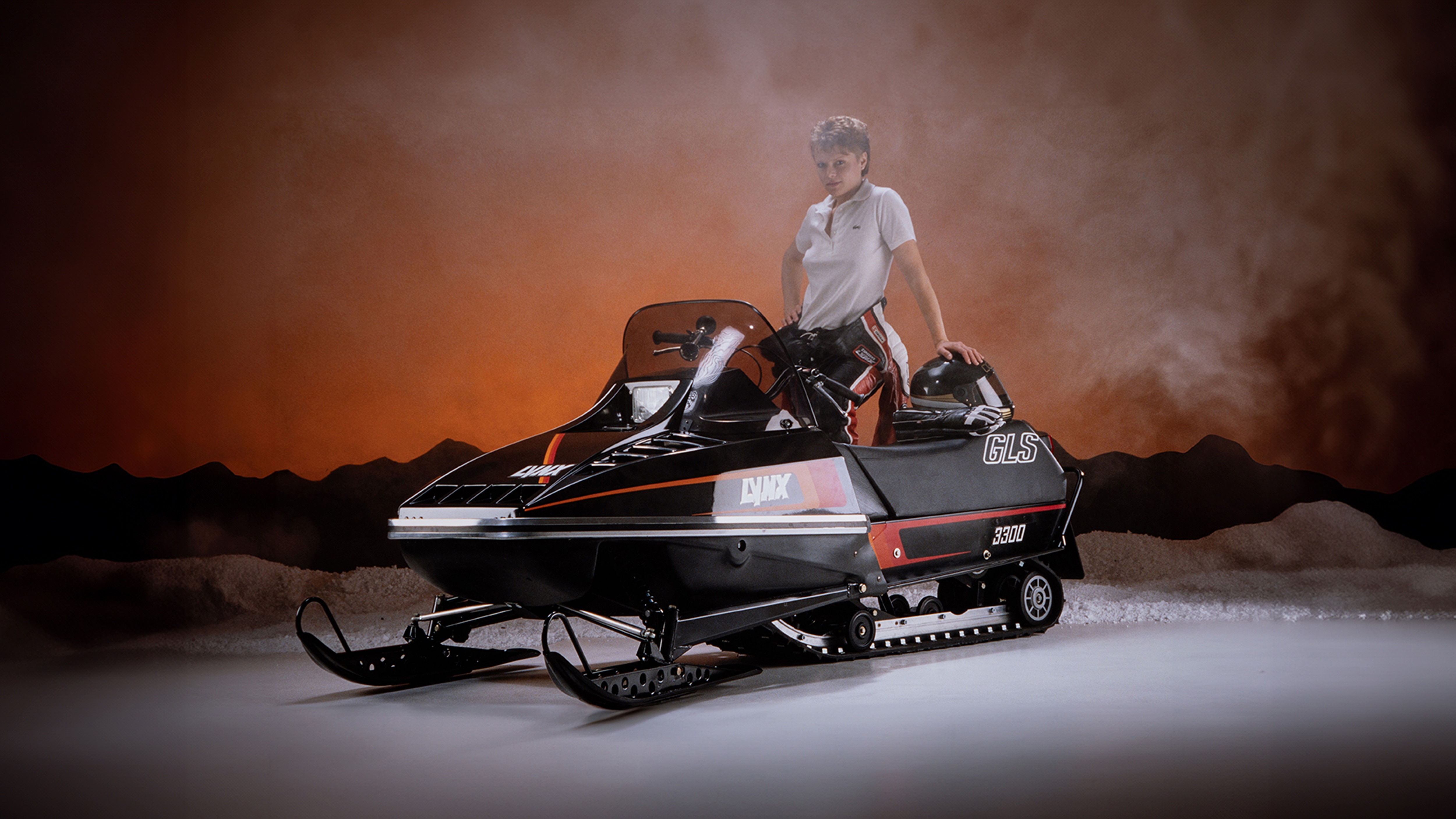 Woman standing with Lynx GLS 3300 sport snowmobile in studio