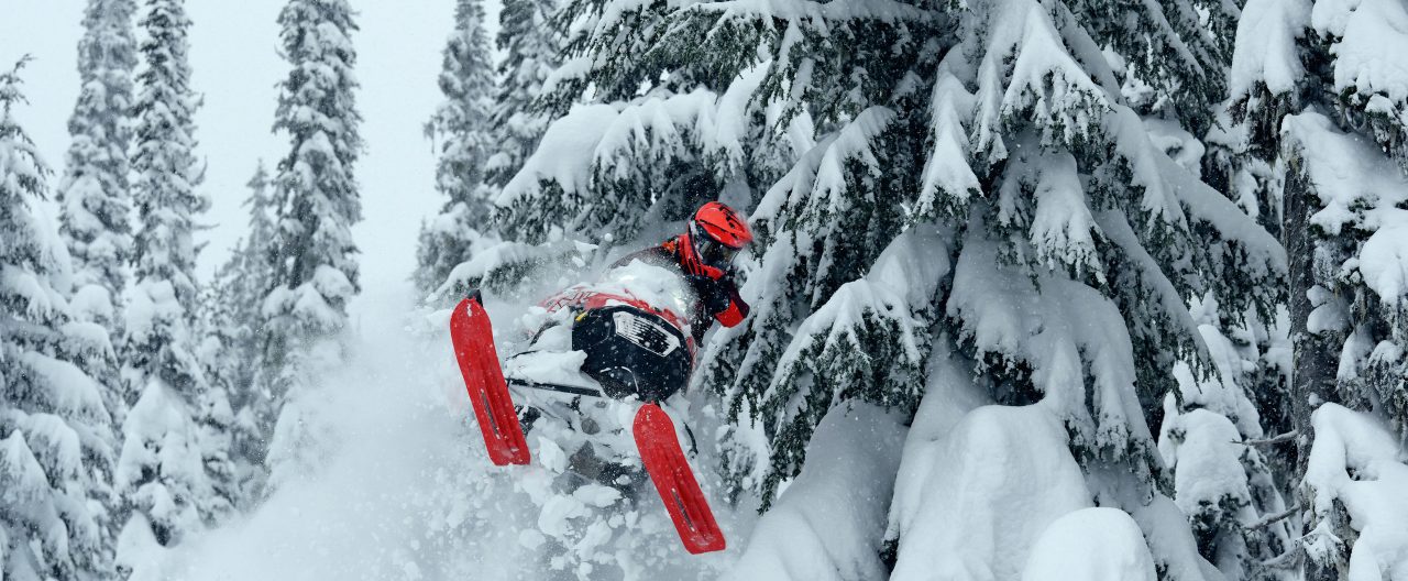 Rider jumping out of deep snow on a 2026 Lynx Shredder snowmobile
