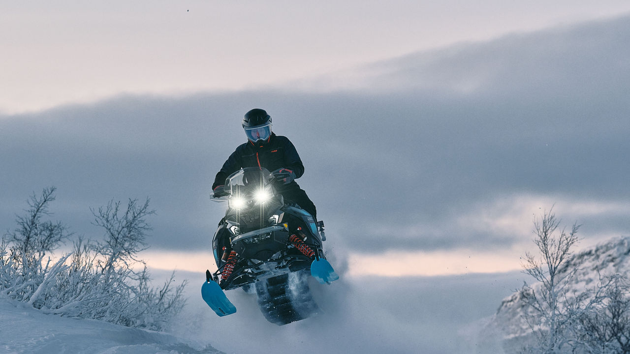 Rider performing a jump on a 2026 Lynx Commander snowmobile