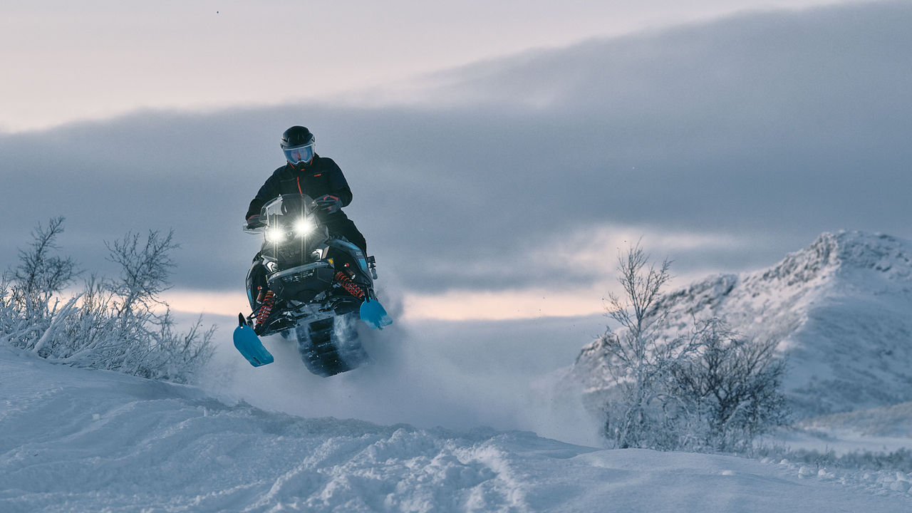 Lynx Brutal RE 2025 snøscooter som kjører opp en bratt skogsbakke