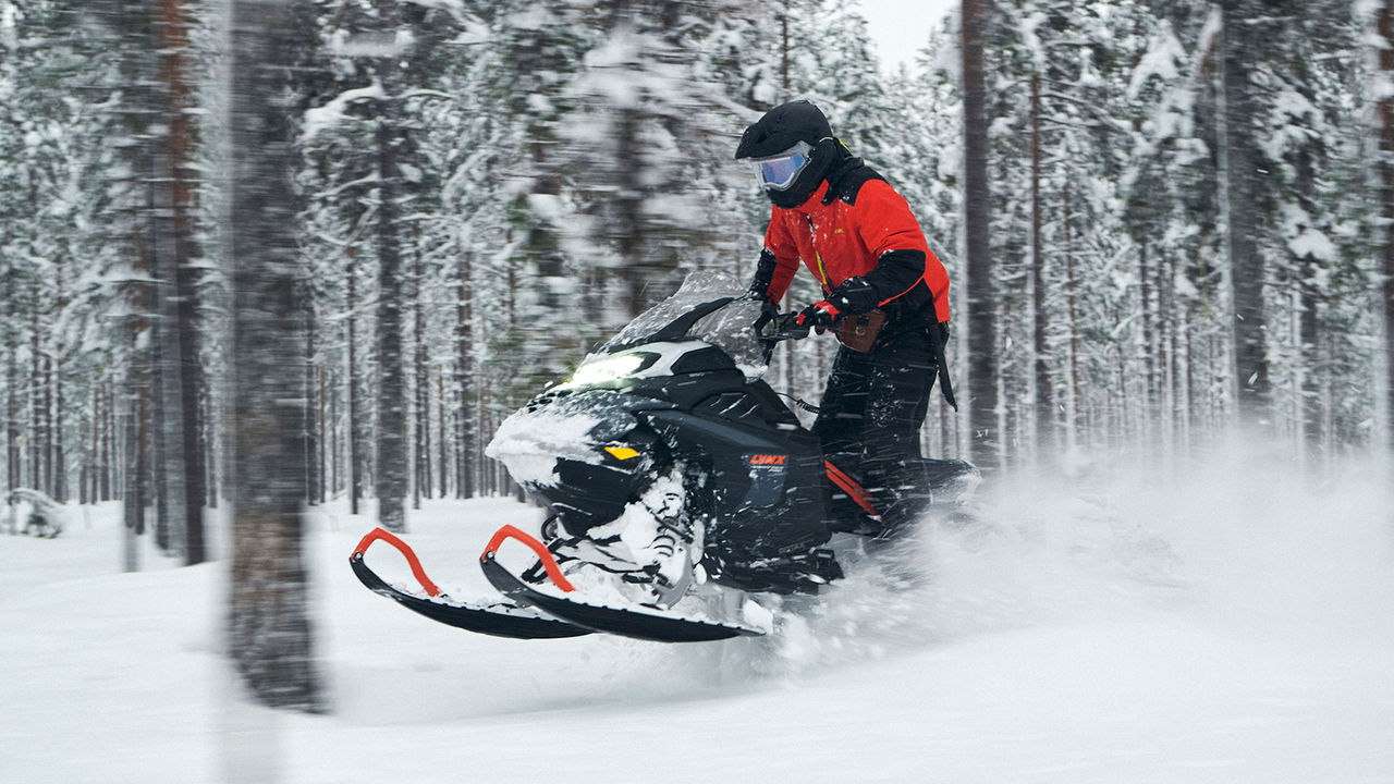 Lynx Brutal RE 2025 snøscooter som kjører opp en bratt skogsbakke